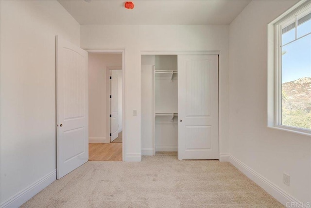 unfurnished bedroom with multiple windows, a closet, and light colored carpet