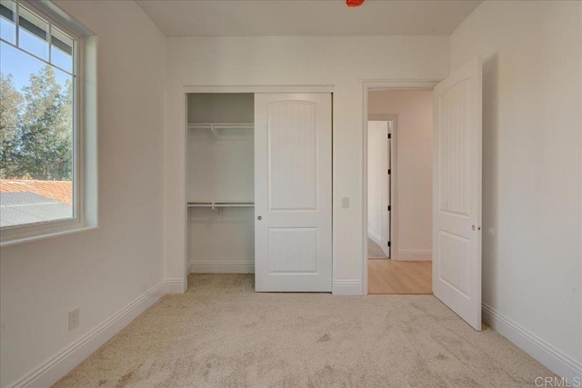 unfurnished bedroom with light carpet, multiple windows, and a closet