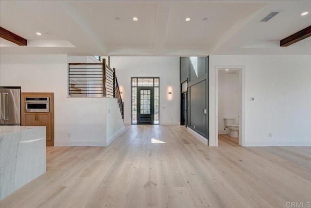 foyer with beam ceiling, light hardwood / wood-style floors, and french doors