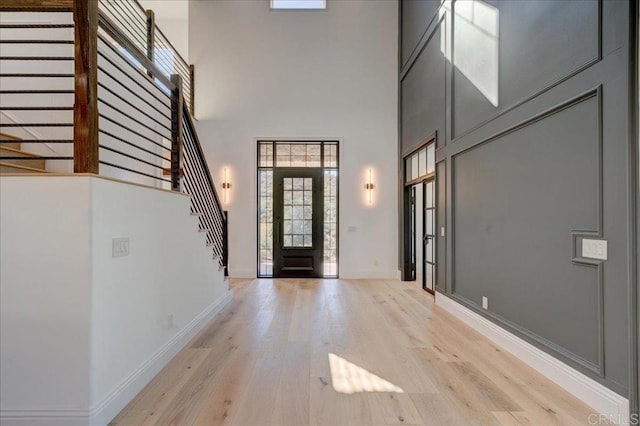 foyer with light wood-type flooring and a towering ceiling