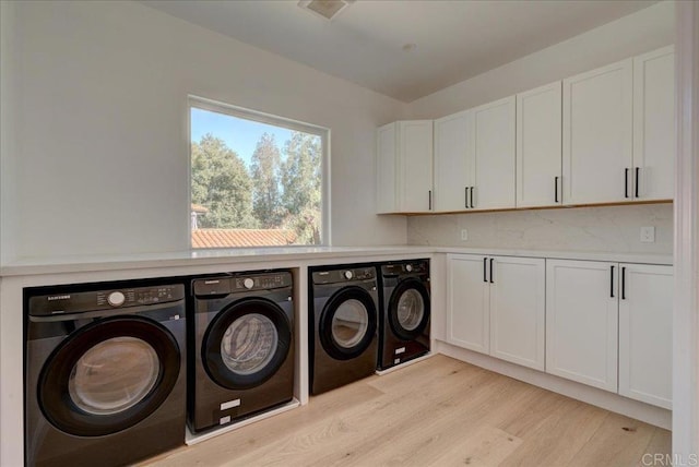 laundry room with washer and clothes dryer, cabinets, and light wood-type flooring