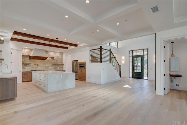 kitchen with a center island, beamed ceiling, pendant lighting, light hardwood / wood-style floors, and custom exhaust hood