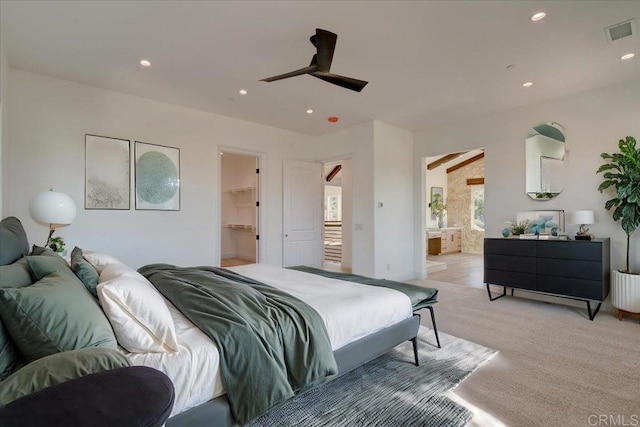 bedroom featuring ensuite bathroom, ceiling fan, a spacious closet, light colored carpet, and a closet