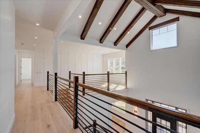 corridor with lofted ceiling with beams and light hardwood / wood-style floors