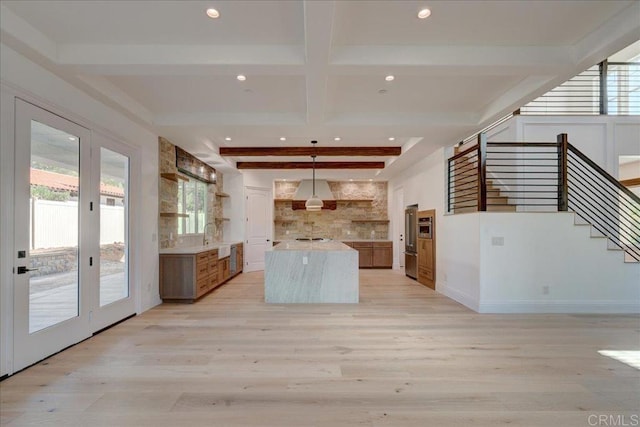 kitchen featuring high end refrigerator, light wood-type flooring, sink, beam ceiling, and hanging light fixtures