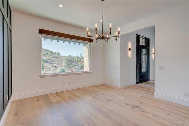 unfurnished dining area featuring a chandelier and light hardwood / wood-style floors