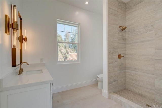 bathroom featuring toilet, a tile shower, vanity, and tile patterned floors