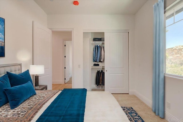 carpeted bedroom featuring multiple windows and a closet