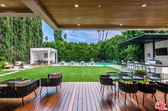 wooden terrace featuring a fenced in pool and exterior kitchen