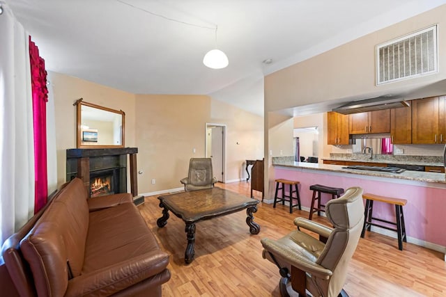 living room with lofted ceiling, sink, and light hardwood / wood-style flooring