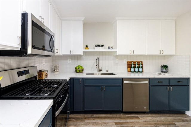 kitchen with white cabinets, dark hardwood / wood-style flooring, blue cabinetry, and appliances with stainless steel finishes