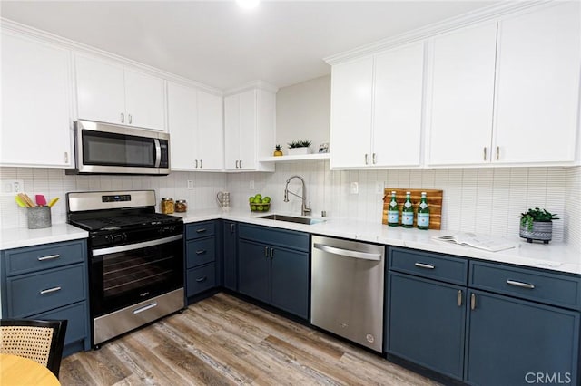 kitchen featuring hardwood / wood-style floors, sink, blue cabinetry, white cabinetry, and stainless steel appliances