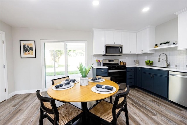 kitchen featuring blue cabinets, sink, light hardwood / wood-style flooring, appliances with stainless steel finishes, and white cabinetry