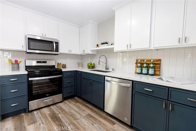 kitchen featuring white cabinetry, sink, stainless steel appliances, blue cabinets, and light wood-type flooring