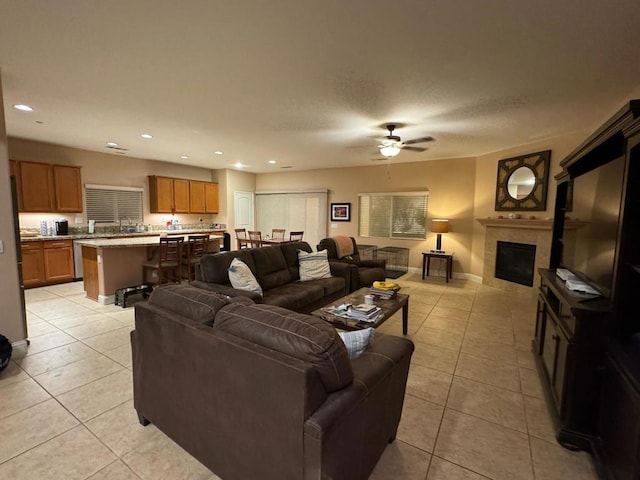 living room featuring ceiling fan, light tile patterned flooring, and a fireplace