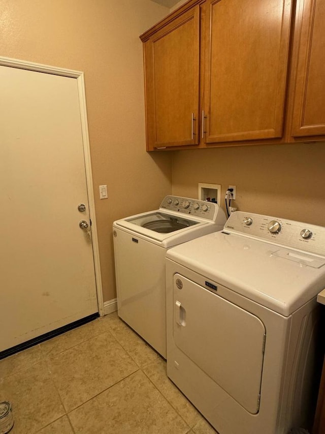 washroom with washing machine and clothes dryer, light tile patterned floors, and cabinets