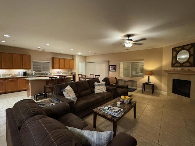 tiled living room featuring ceiling fan and a tiled fireplace