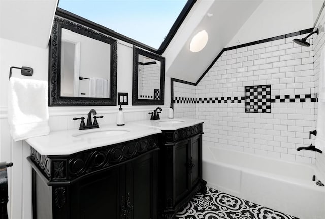 bathroom with vaulted ceiling, vanity, and tiled shower / bath