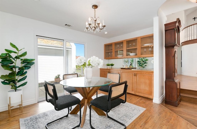 dining space with light hardwood / wood-style floors and a chandelier