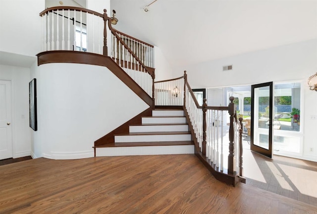 staircase featuring a high ceiling, wood-type flooring, and french doors