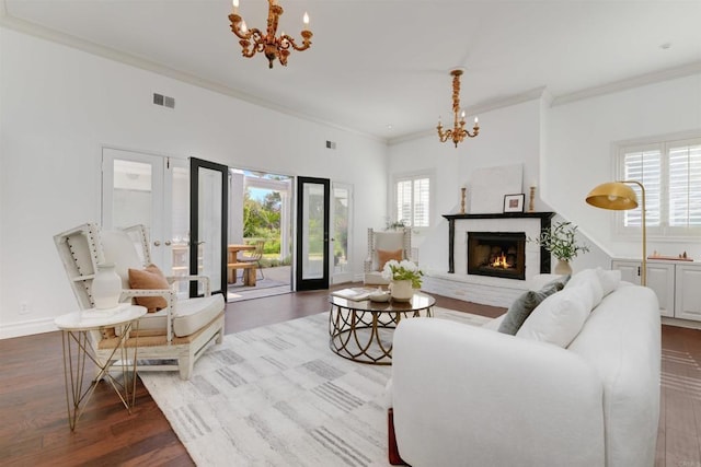 living room featuring french doors, crown molding, an inviting chandelier, and light hardwood / wood-style flooring