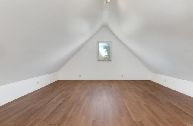 additional living space with hardwood / wood-style flooring and vaulted ceiling