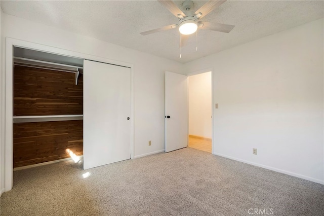 unfurnished bedroom featuring ceiling fan, a closet, light carpet, and a textured ceiling