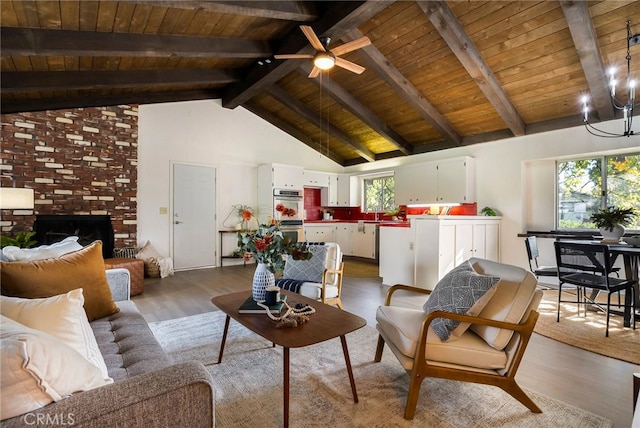 living room with wood ceiling, hardwood / wood-style floors, high vaulted ceiling, a brick fireplace, and beamed ceiling