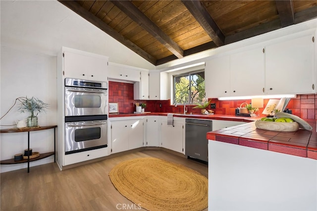 kitchen with white cabinetry, appliances with stainless steel finishes, tile counters, and tasteful backsplash