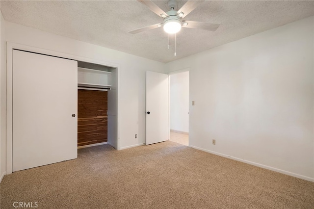 unfurnished bedroom featuring ceiling fan, light colored carpet, a closet, and a textured ceiling