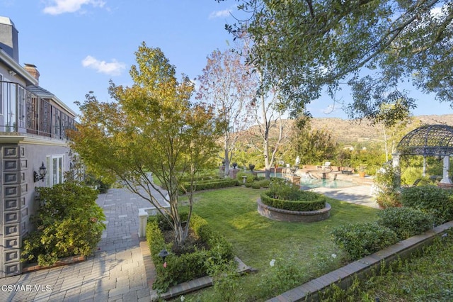 view of yard with a mountain view, a patio, and a balcony