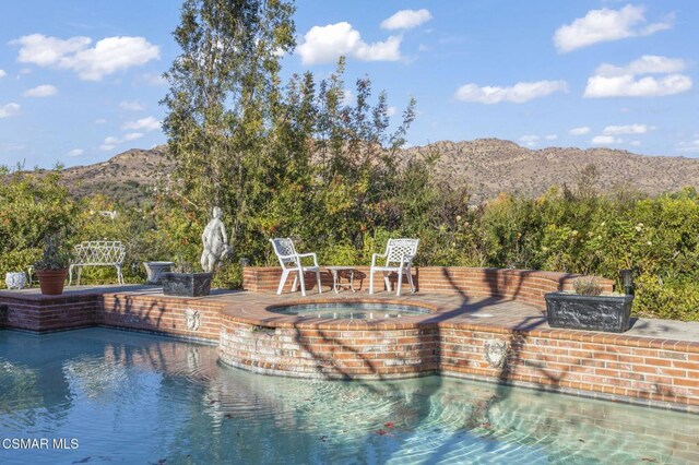 view of pool featuring a mountain view and an in ground hot tub