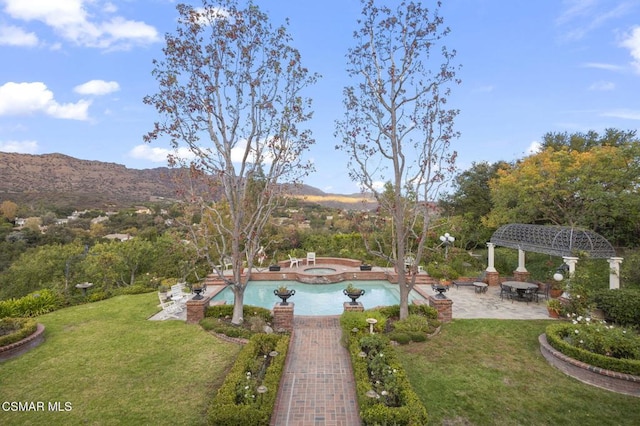 view of swimming pool featuring an in ground hot tub, a mountain view, and a lawn