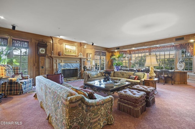 carpeted living room featuring a fireplace and wooden walls