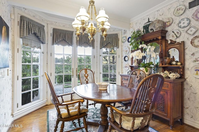 dining area featuring hardwood / wood-style floors, ornamental molding, and a chandelier