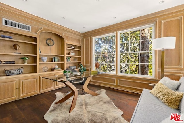 home office featuring built in shelves, dark hardwood / wood-style flooring, and wood walls