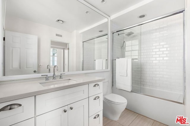 full bathroom with vanity, toilet, and enclosed tub / shower combo