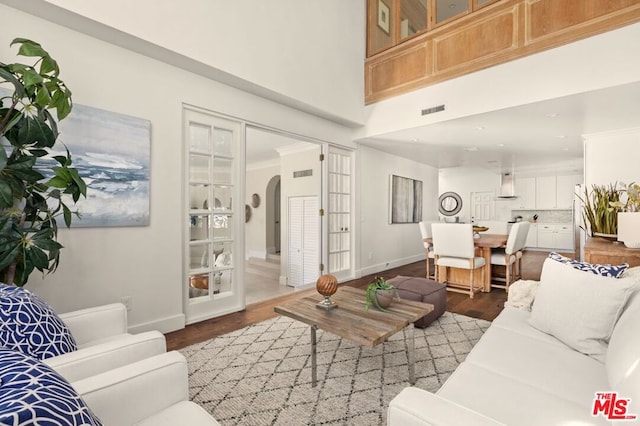 living room featuring wood-type flooring, a high ceiling, and french doors