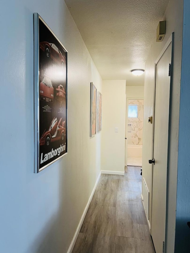 hall featuring light hardwood / wood-style floors and a textured ceiling