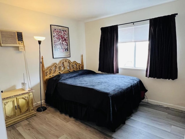 bedroom featuring a wall mounted air conditioner and light hardwood / wood-style floors