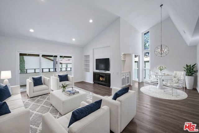 living room with hardwood / wood-style floors, a notable chandelier, built in features, and high vaulted ceiling