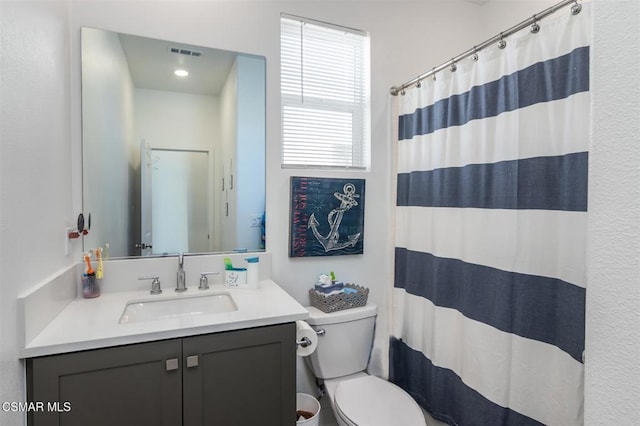 bathroom with walk in shower, vanity, and toilet