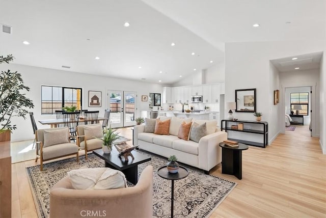 living area with recessed lighting, light wood finished floors, and high vaulted ceiling