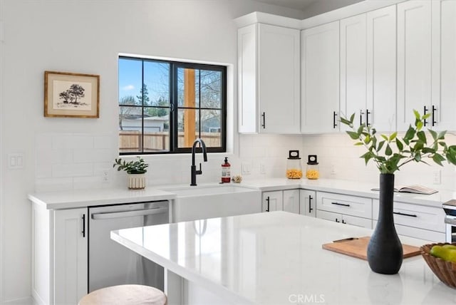 kitchen featuring a sink, decorative backsplash, light countertops, white cabinets, and dishwasher