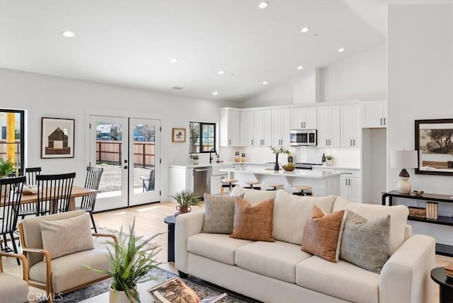 living area featuring recessed lighting, french doors, light wood-style floors, and high vaulted ceiling