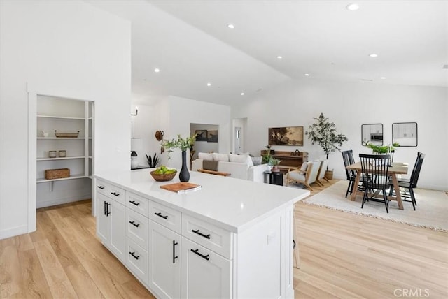 kitchen featuring white cabinetry, vaulted ceiling, light wood-type flooring, and a kitchen island