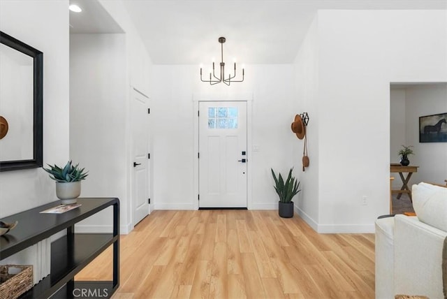 foyer entrance featuring a notable chandelier, baseboards, and light wood-style floors