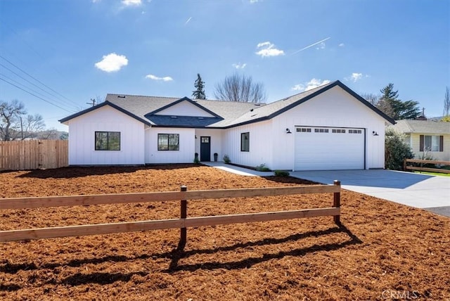 view of front facade with concrete driveway, board and batten siding, an attached garage, and fence