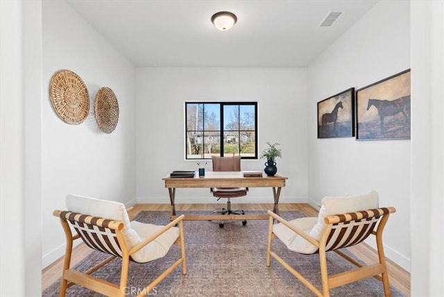 office area with wood finished floors, visible vents, and baseboards