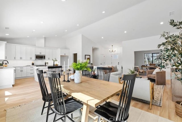 dining space featuring light wood finished floors, visible vents, recessed lighting, a notable chandelier, and high vaulted ceiling